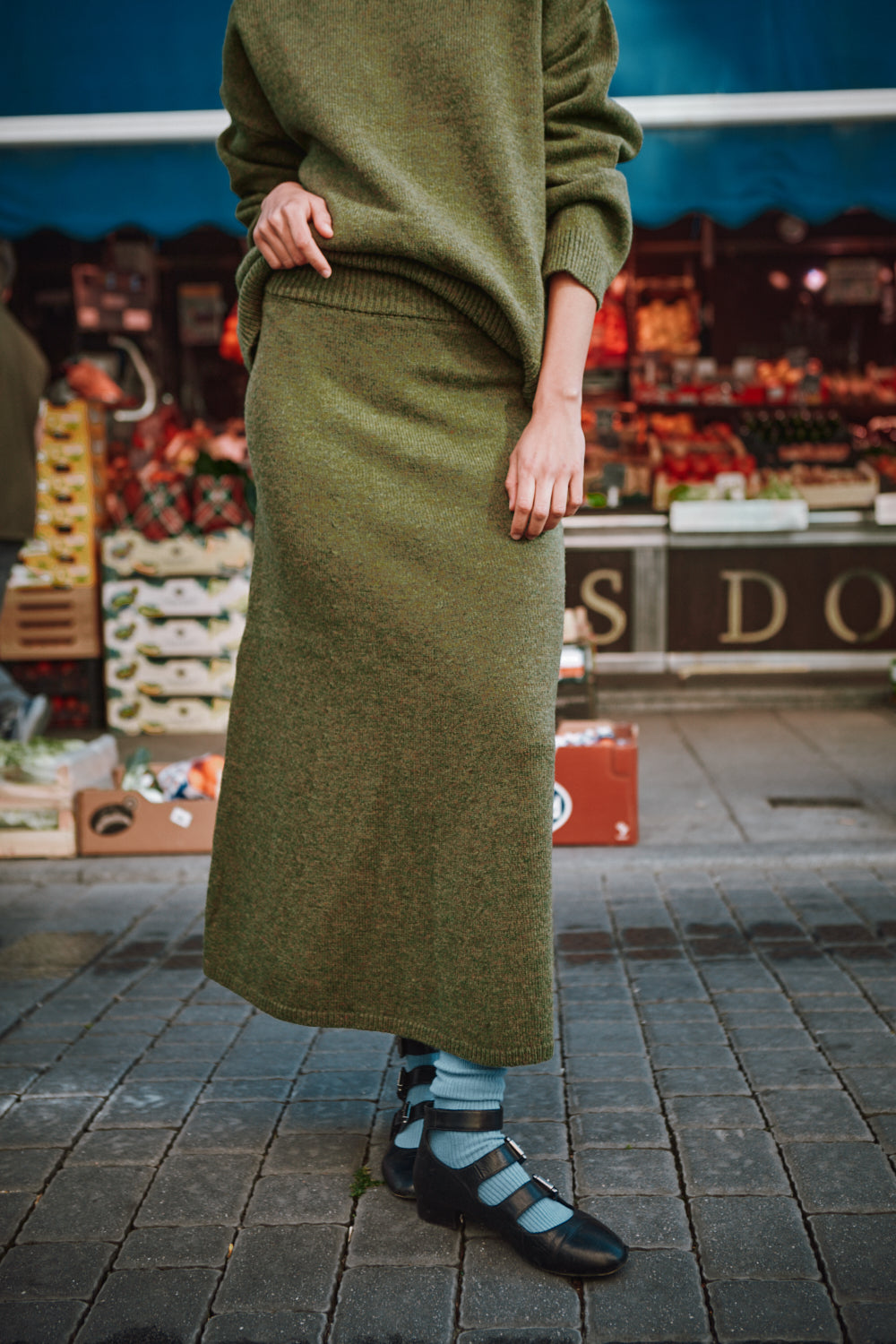 Person wearing a green outfit with a long skirt in an urban setting