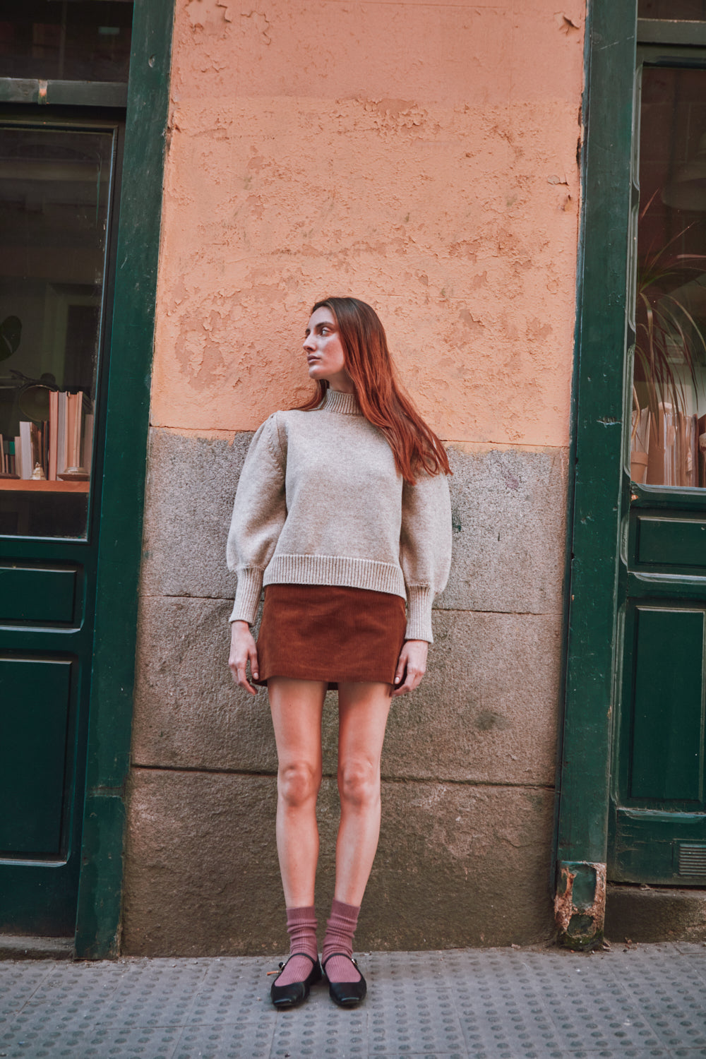 Femme portant un pull beige pull L'ENVERS devant un immeuble