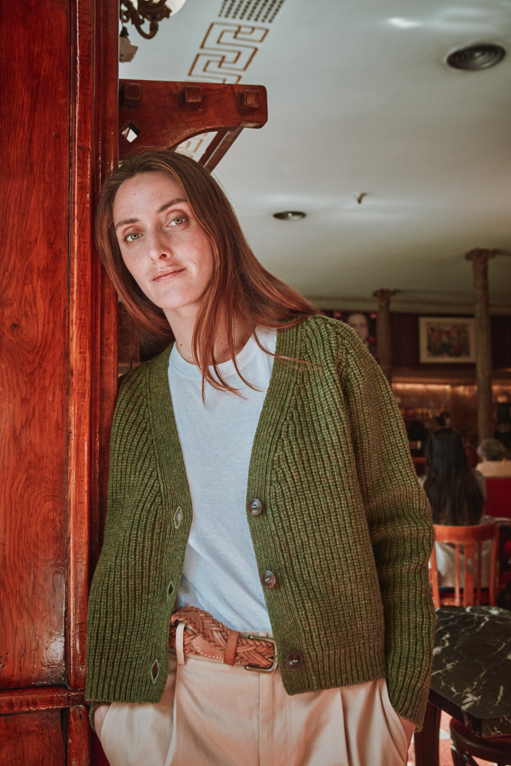 Person wearing a green cardigan in an indoor setting