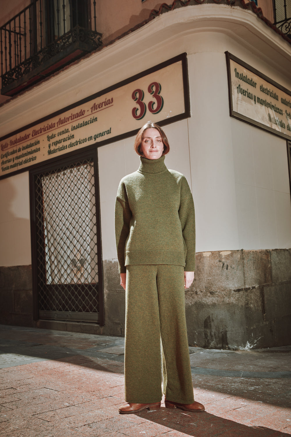 Person wearing a green outfit standing in front of a building 