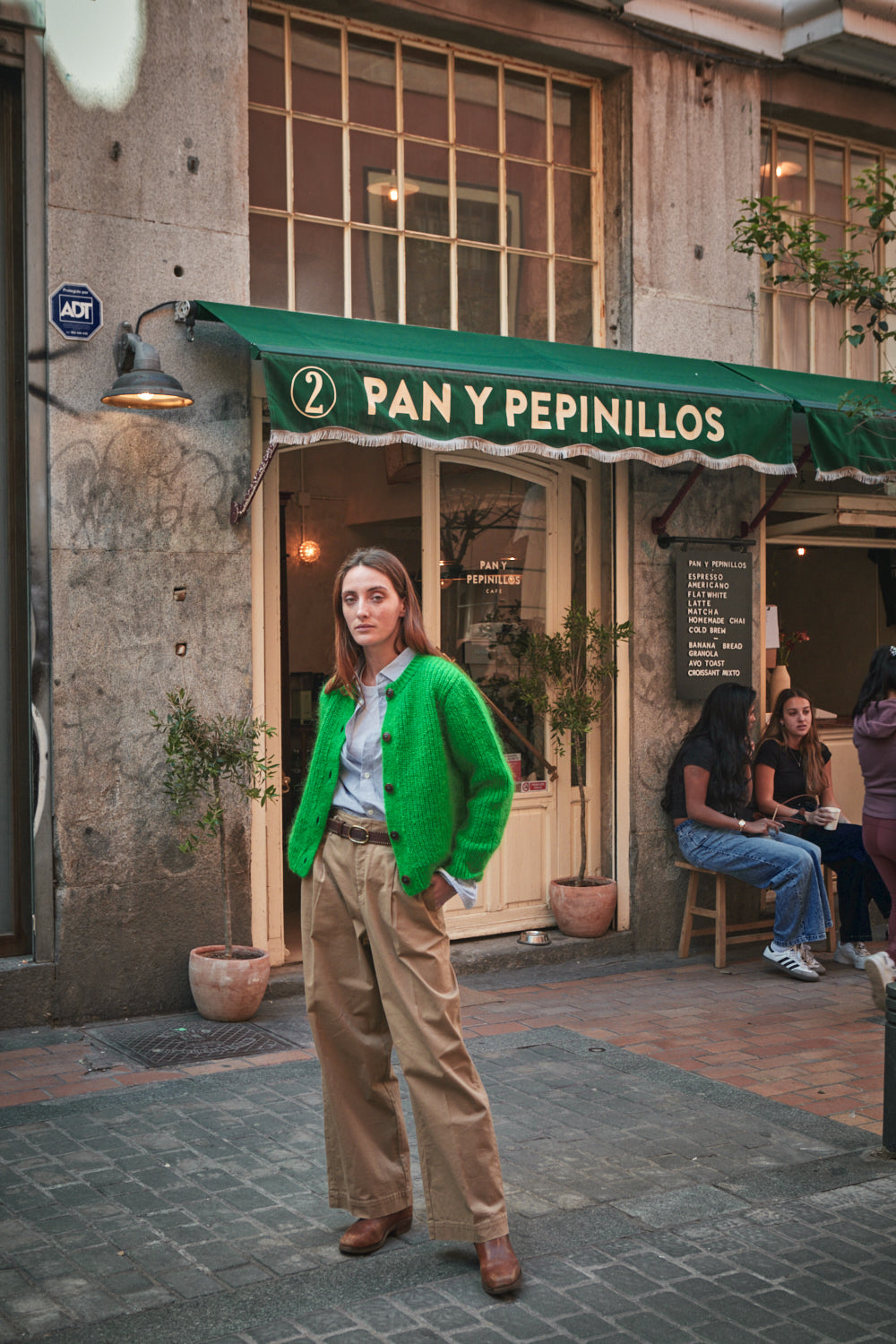 Femme en gilet vert devant un magasin 