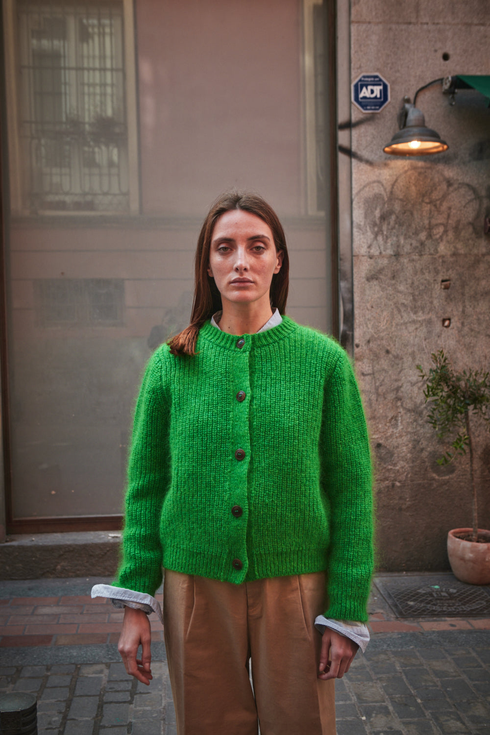Femme portant un gilet vert debout dans un environnement urbain