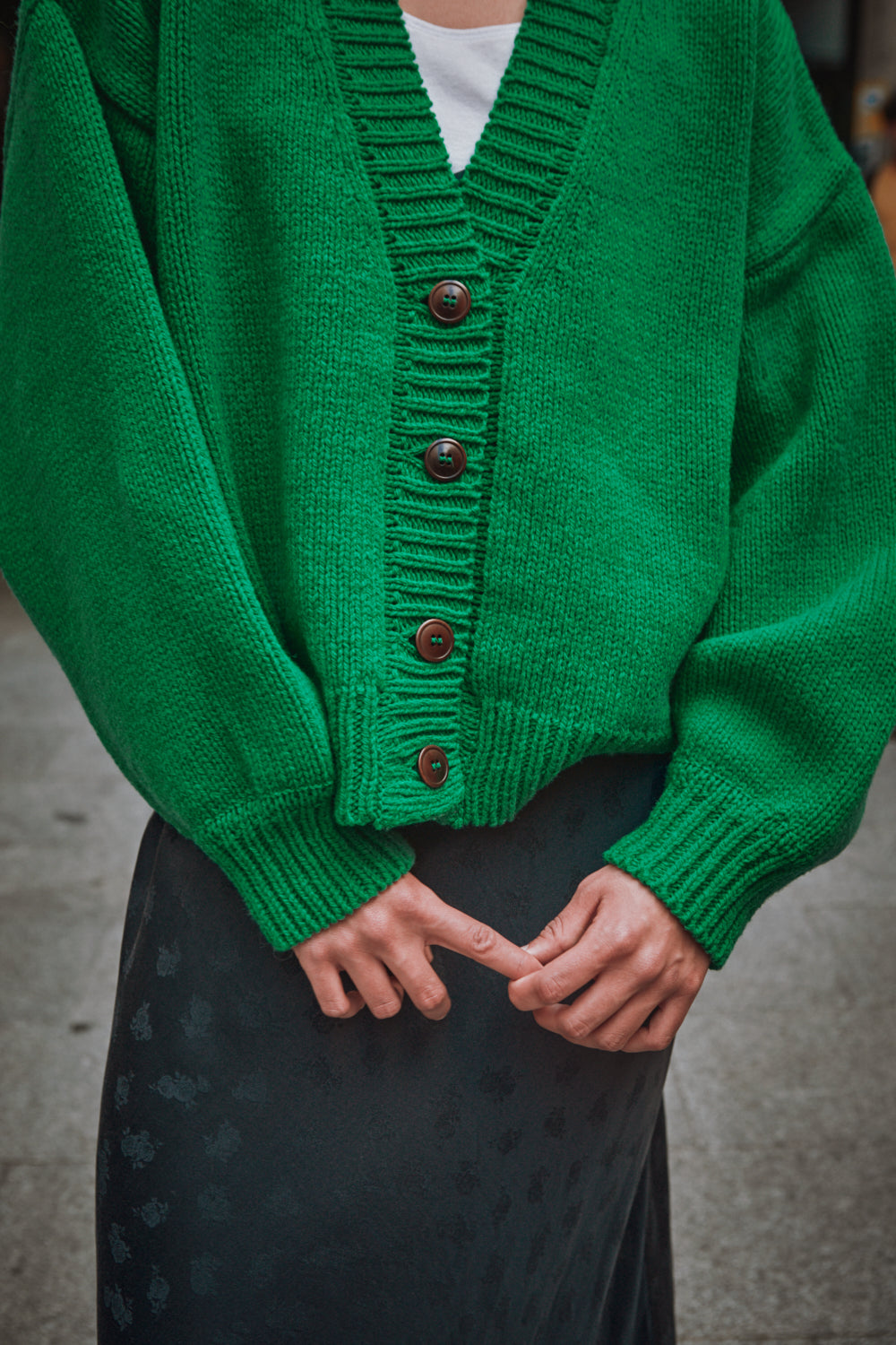 gilet en tricot vert porté par une personne sur fond flou