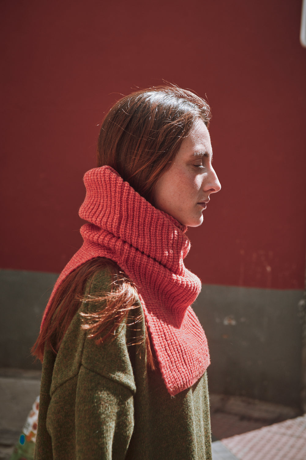 Personne portant une cagoule en tricot corail contre un mur rouge