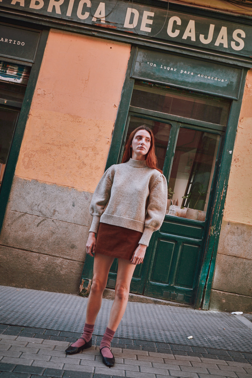 Femme portant un pull beige pull L'ENVERS devant un immeuble