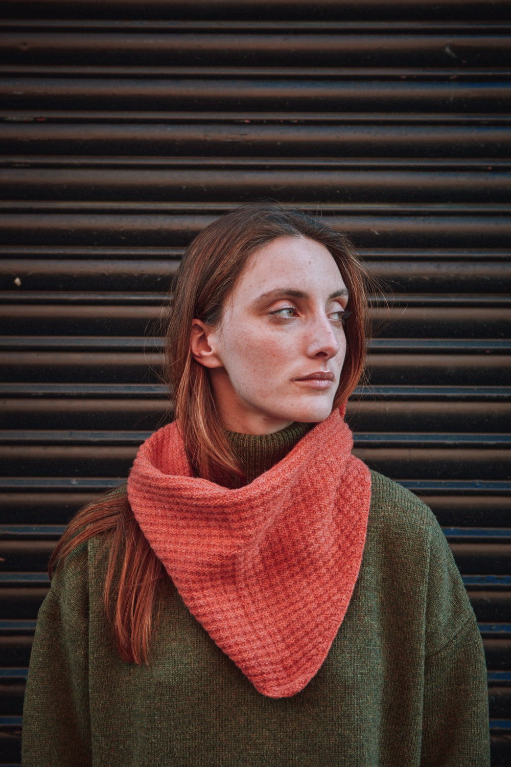 Femme portant un foulard corail sur fond sombre