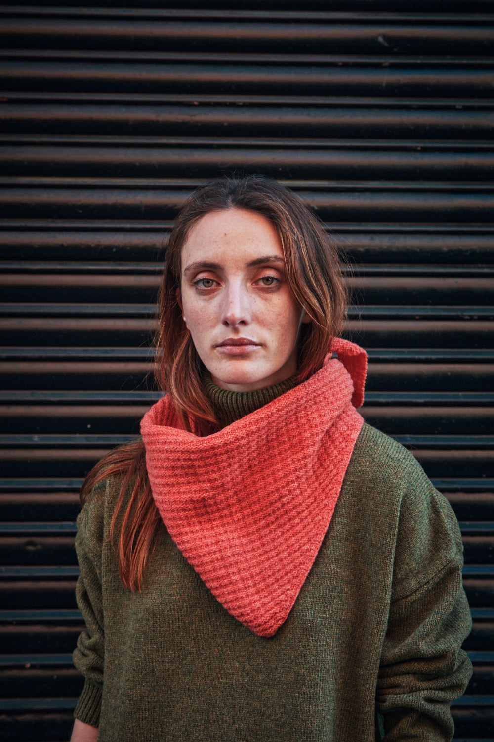 Femme portant un foulard corail sur fond sombre