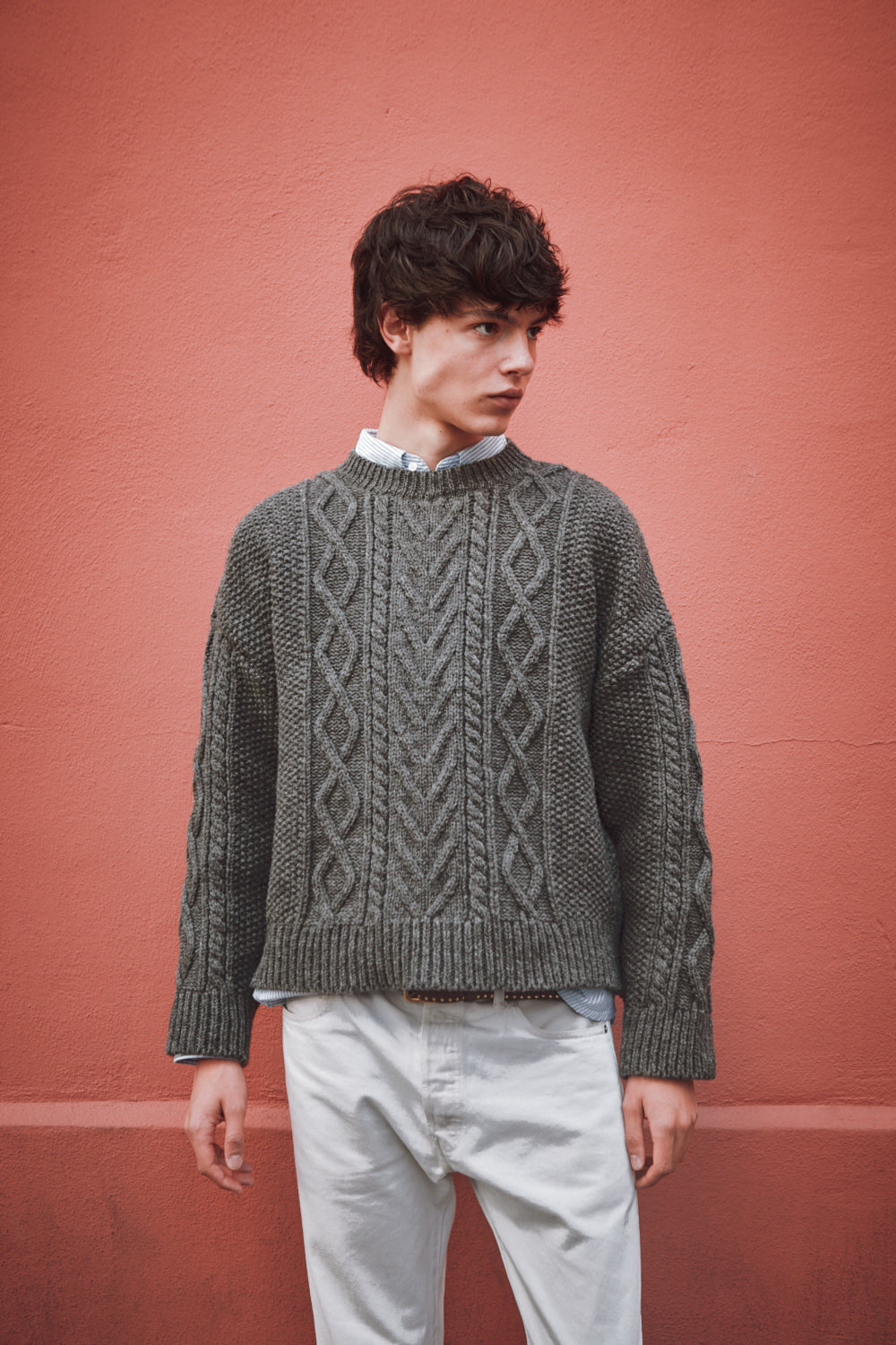Homme portant un pull motifs irlandais sur fond rose
